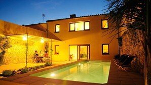 A swimming pool with a stone wall and a covered patio area with chairs. - Ca l'Helena. Enjoy the Penedès, the wine region of Barcelona (Castellet i la Gornal)
