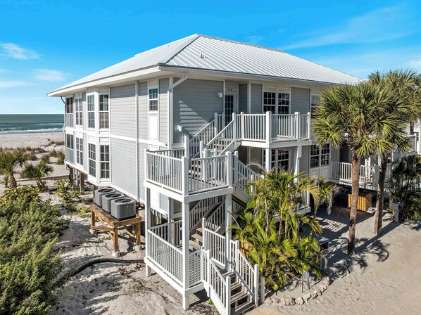 A multi-story beachfront building with balconies, a pool area, and a view of the ocean.