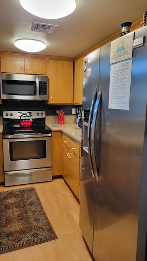 A modern kitchen with stainless steel appliances, wooden cabinets, and a built-in microwave.