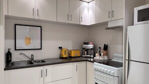 A modern kitchen with white cabinets, a sink, a toaster, a coffee machine, and a stove.