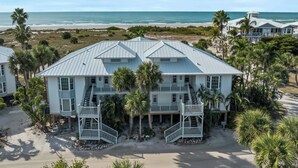 Une propriété située en bord de mer, comprenant plusieurs bâtiments, dont une maison principale dotée d’un balcon et une dépendance plus petite.