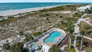Vue aérienne d’un complexe hôtelier doté d’une piscine, d’un accès à la plage et de villas en bord de mer.