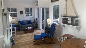Una sala de estar acogedora con piso de madera, un sofá, un sillón, una mesa y una maqueta de un velero.