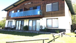 A two-story building named Yowie Lodge with a balcony, large windows, and outdoor seating. - Yowie 3 - (Yowie Lodge) (Jindabyne)