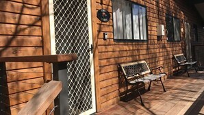 A wooden building with a large door, two windows, and a bench outside. - Yowie 3 - (Yowie Lodge) (Jindabyne)
