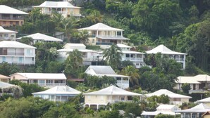A cluster of houses with white and pastel-colored roofs, surrounded by dense tropical vegetation. - Hibiscus: calm and breathtaking views for this T3 overlooking the bay of Fort de France (Les Trois-Îlets)