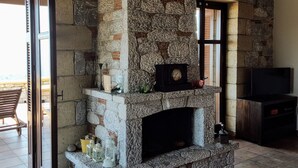 Una chimenea de piedra con un reloj, un farol y velas sobre la repisa.