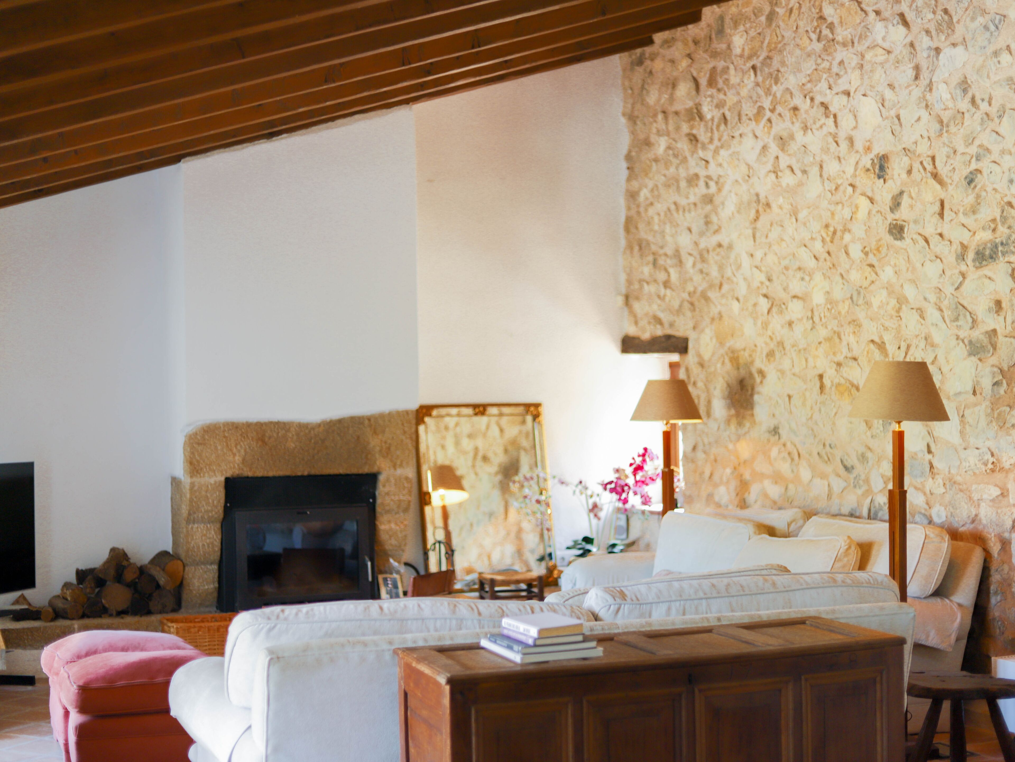 A cozy living room with a stone wall, a fireplace, a sofa, and a television.