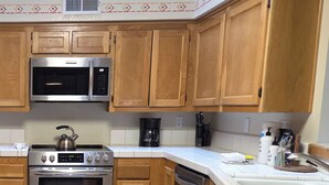 A kitchen with wooden cabinets, stainless steel appliances, and a tiled floor.