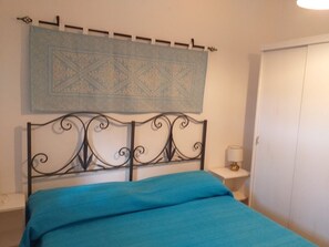 Un dormitorio con cama, mesita de noche, un adorno en la pared y armario.