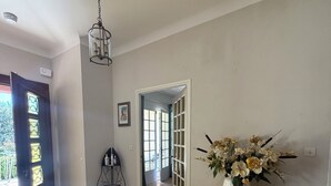 A hallway with a door, a staircase, and a console table with a vase of flowers.