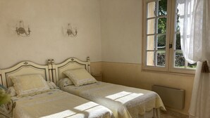 A room with two beds, a window with curtains, and a radiator.