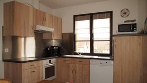 A compact kitchen with wooden cabinets, a microwave, a coffee maker, and a dishwasher.