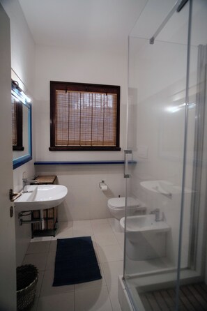 Une salle de bain avec deux lavabos, des toilettes et une douche à parois de verre.