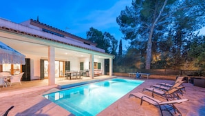 A swimming pool with lounge chairs, an outdoor dining area, and a covered patio.