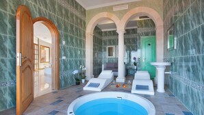 A spa area with a hot tub, lounge chairs, and a green door.