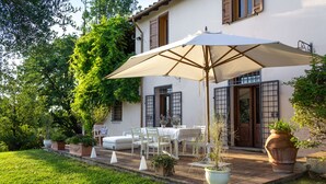 A patio with outdoor furniture, a large umbrella, and potted plants.