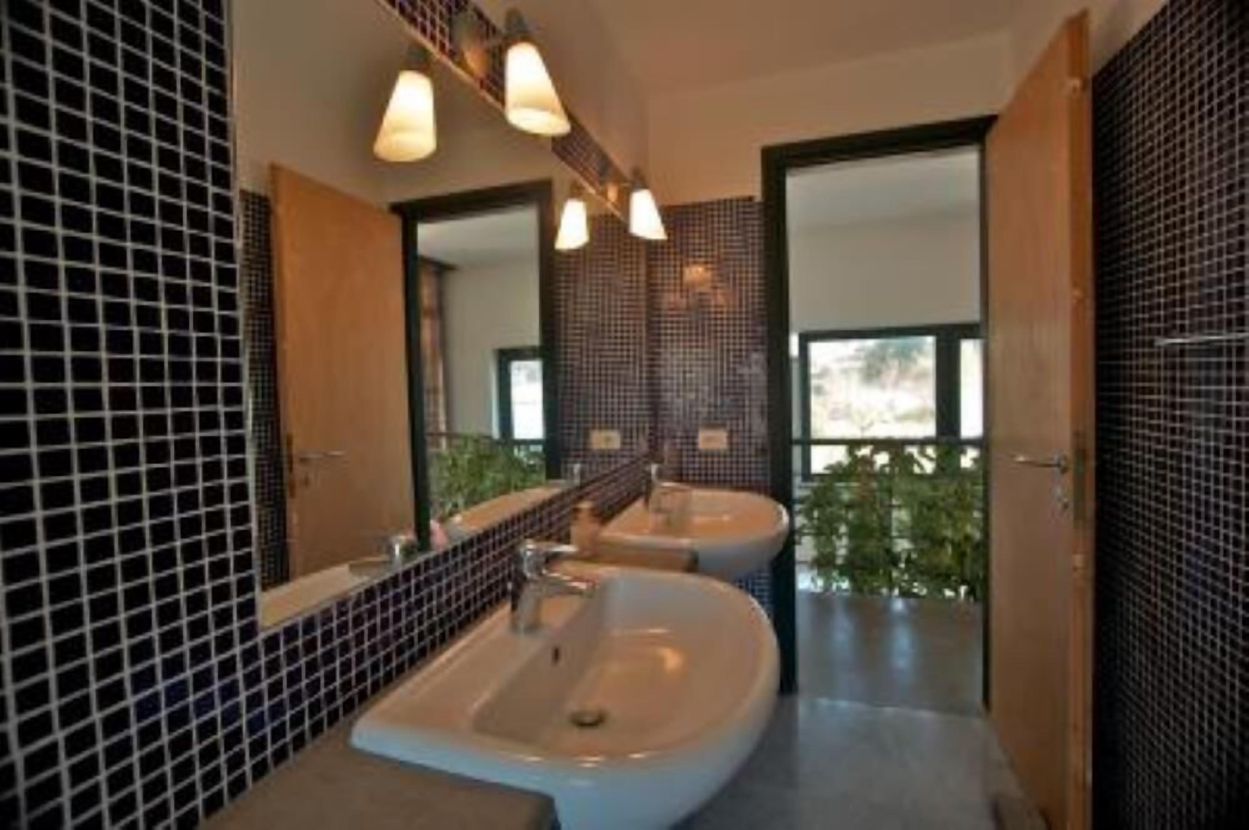 A modern bathroom with two sinks, a large mirror, and a view of greenery outside.