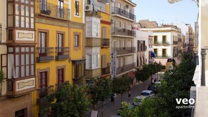 A street view with multi-story buildings, balconies, and parked cars. - Studio in Macarena (Sevilla)