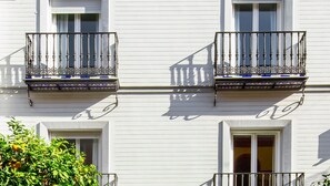 A building with white exterior walls, two balconies with ornate metal railings, and windows with white frames.
