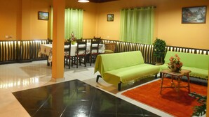 A dining area with a table and chairs, a sofa, and a small table with a vase. - Villa B Apartments (Ponta do Sol)