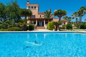 Une grande maison en pierre avec une piscine devant.
