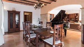 Een eethoek met een piano, houten stoelen, een gedekte eettafel voor vier personen en een grote kast.