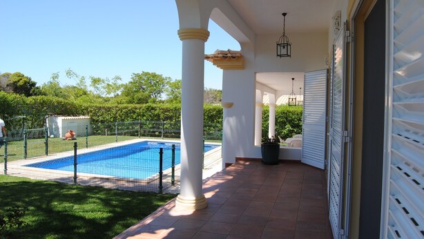 A covered outdoor area with a pool, white columns, and a garage door. - Luxury 4 bedroom Villa with private pool and garden (Sta. Eulalia)