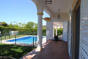 Un espacio al aire libre cubierto con piscina, columnas blancas y una puerta de garaje.