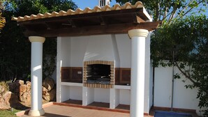 An outdoor patio with a built-in grill, white columns, and a tiled floor. - Luxury 4 bedroom Villa with private pool and garden (Sta. Eulalia)