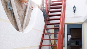 A red metal staircase leading to a kitchen area with cabinets and a microwave. - House / Villa - Fuseta (Fuseta)