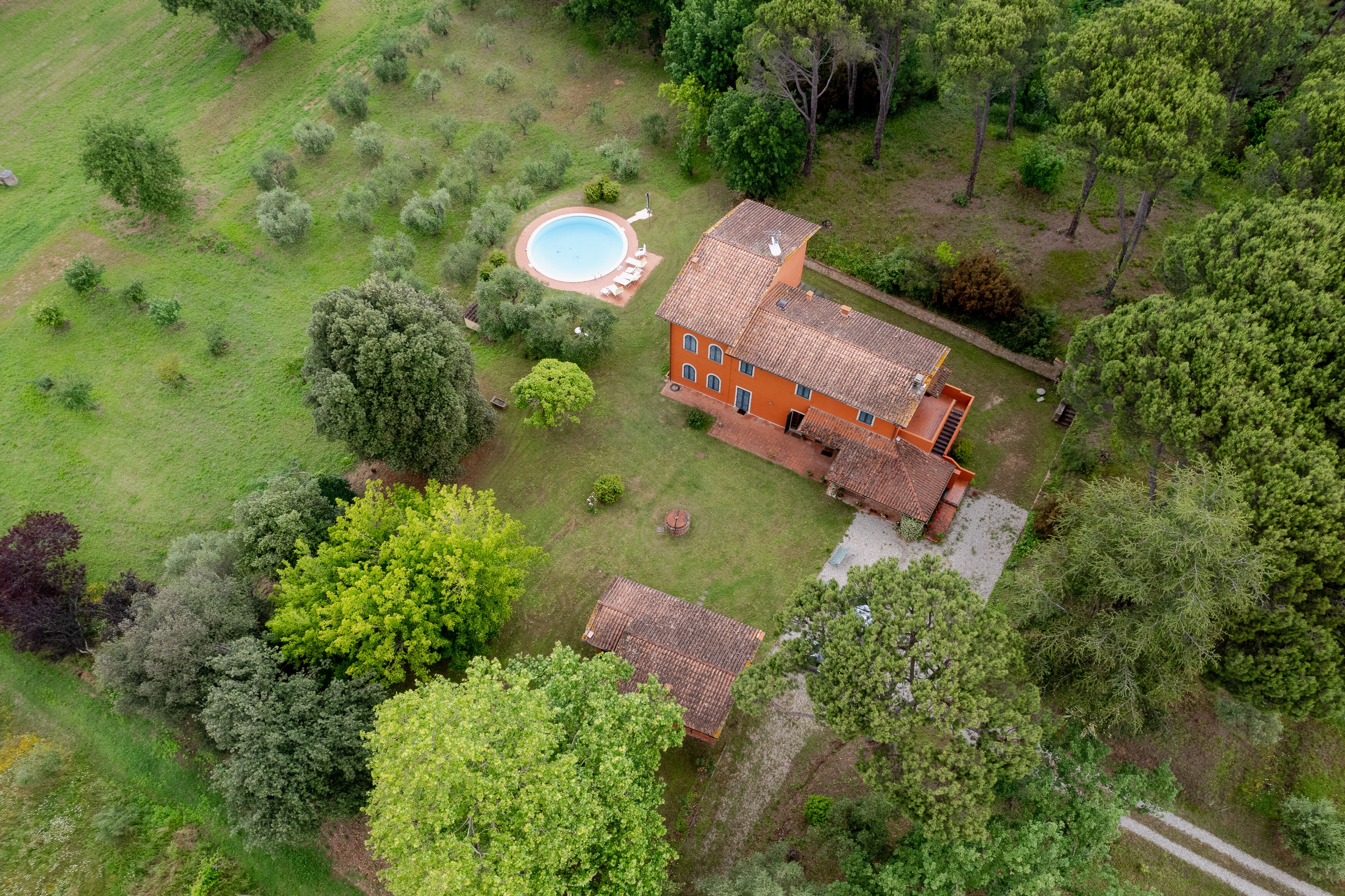 Vue aérienne d’une maison avec une piscine, entourée d’une végétation luxuriante et d’arbres.