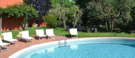 A swimming pool with white lounge chairs and a brick deck.