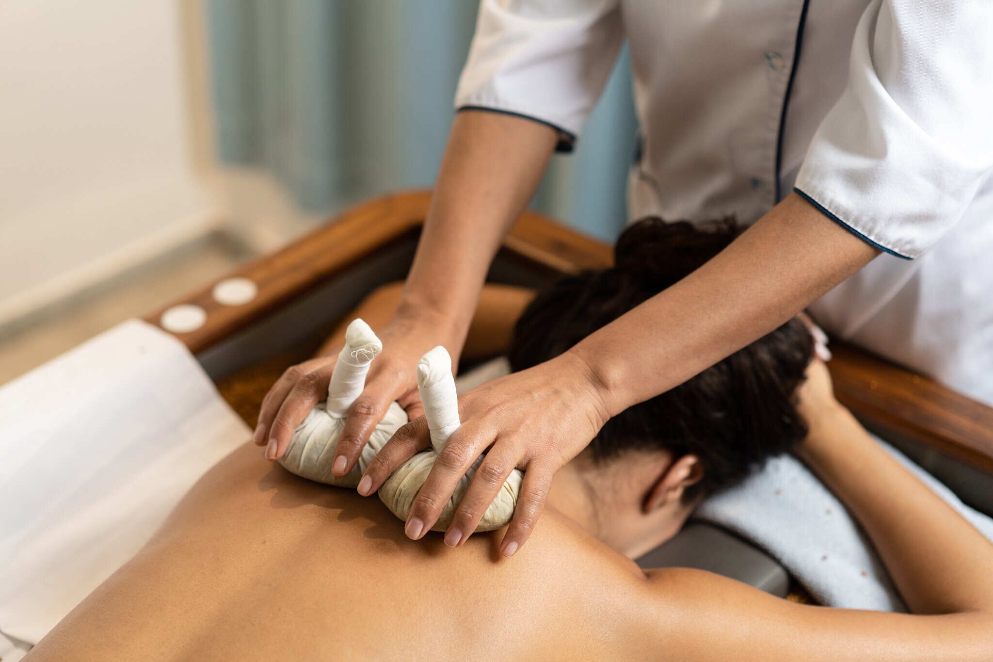 A massage therapy session in progress with a therapist using a stone on a client's back.