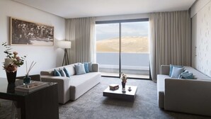 Une chambre d’hôtel moderne avec deux canapés, une table basse, une lampe sur pied et une grande fenêtre donnant sur le désert.