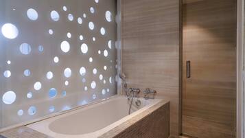 A modern bathroom with a freestanding bathtub, a shower with a handheld showerhead, and a wooden door.