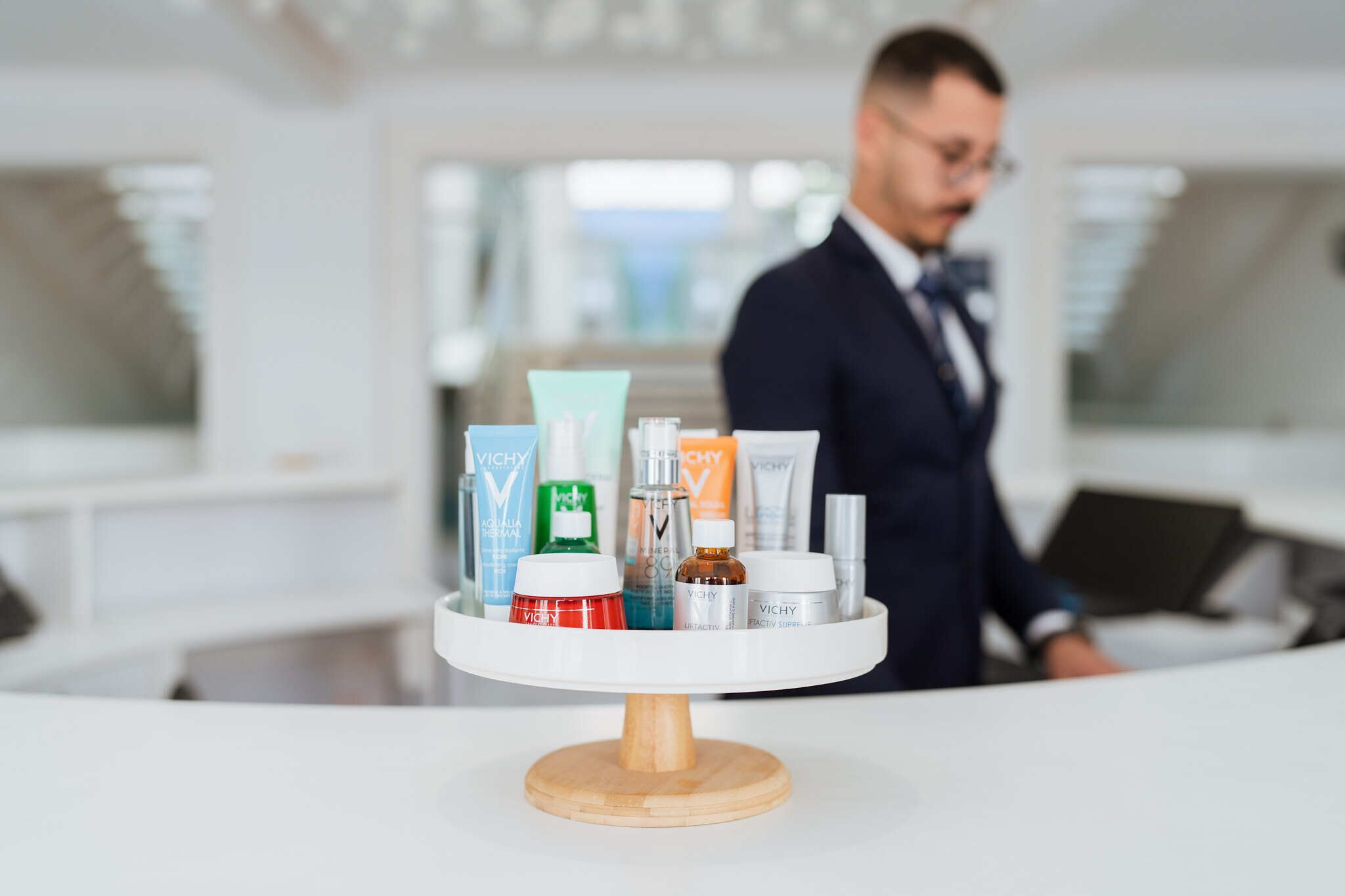 Zona de recepción de hotel con un mostrador blanco que exhibe diversos productos para el cuidado de la piel.