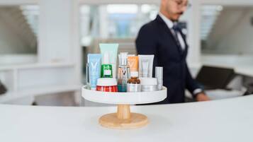 Zona de recepción de hotel con un mostrador blanco que exhibe diversos productos para el cuidado de la piel.