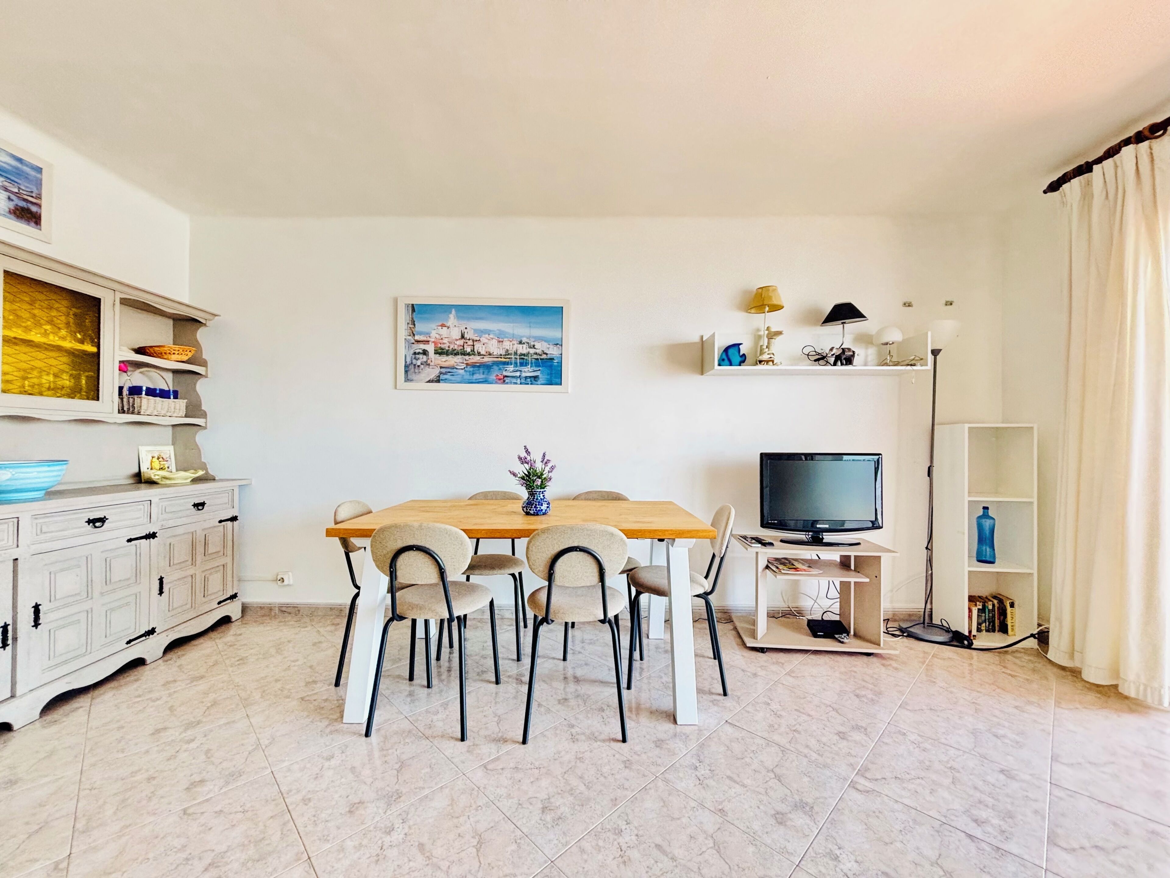 Un coin repas avec une table en bois, des chaises, un téléviseur et une bibliothèque.