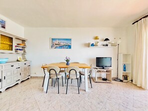 Un comedor con una mesa de madera, sillas, un televisor y una estantería.