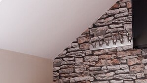 A corner room with a stone wall, a cushioned armchair, and a wooden floor. - Chic Designed Themed  Apartment In The Edinburgh City Centre (Edinburgh)