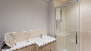 A bathroom with a white sink, a mirror, and a glass shower enclosure. - Chic Designed Themed  Apartment In The Edinburgh City Centre (Edinburgh)