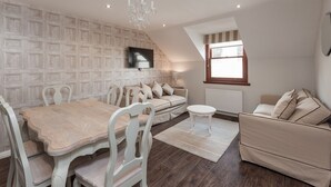 A dining area with a wooden table and chairs, a sofa, and a small round table. - Chic Designed Themed  Apartment In The Edinburgh City Centre (Edinburgh)