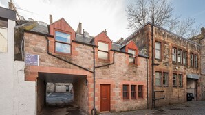 A stone building with a car park entrance, a wooden door, and a brick facade. - Chic Designed Themed  Apartment In The Edinburgh City Centre (Edinburgh)