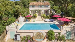 Une maison à deux étages dotée d’une piscine, d’un espace extérieur aménagé et d’un escalier menant à l’entrée.