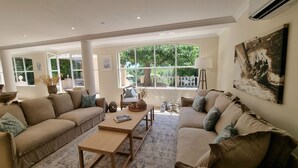 Un salon spacieux comprenant deux canapés, une table basse et une grande fenêtre offrant une vue sur l’extérieur.