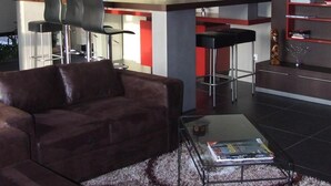 Ein modernes Wohnzimmer mit einem braunen Ledersofa, einem Glastisch und einem roten Bücherregal.
