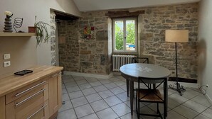 Una habitación amplia con tragaluces, paredes de piedra, una mesa de comedor y una zona de cocina.