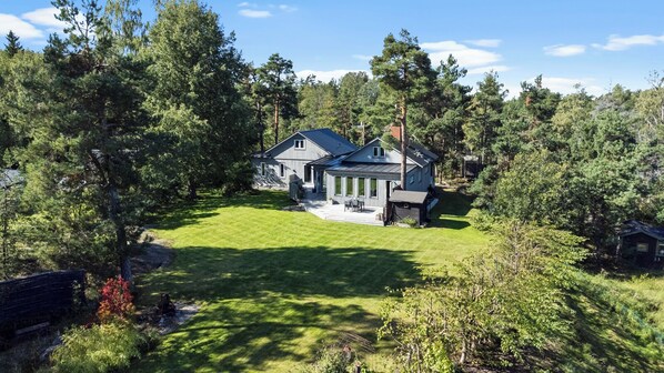 A large house with a well-maintained lawn, surrounded by dense trees. - Modern house 15 min from Center of Stockholm (Boo)