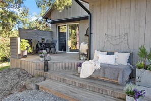 A wooden deck with a bed, a table, and chairs. - Modern house 15 min from Center of Stockholm (Boo)